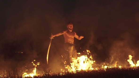 Free Fighter Training with Sword in the Burning Night Field. Slowly alt