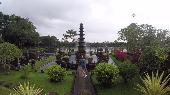 Young Tourist Girl Goes to a Beautiful Fountain in Hindu Balinese Water Palace Tirta Gangga