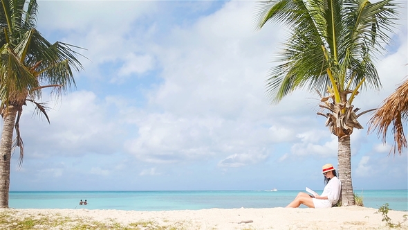 Young Woman Reading Book during Tropical White Beach