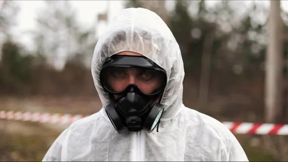 Man in Bio-hazard Suit and Gas Mask Walks and Looks Straight Into the ...