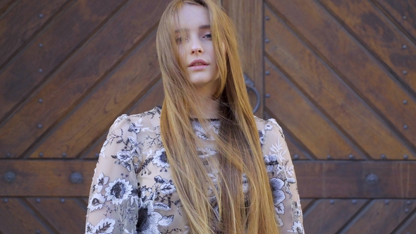 Girl with Long Wheat-colored Hair. Looks Directly Into the Camera, the Hair Develops the Wind