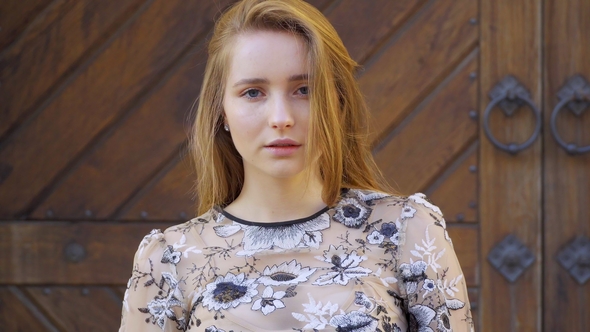 Girl with Long Wheat-colored Hair. Looks Directly Into the Camera, the Hair Develops the Wind