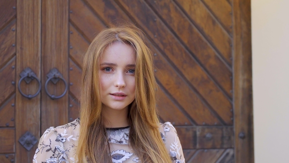 Girl with Long Wheat-colored Hair. Looks Directly Into the Camera, the Hair Develops the Wind