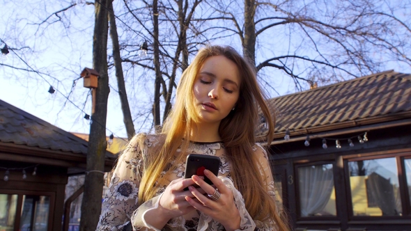 A Girl Reads Messages in Her Mobile Phone