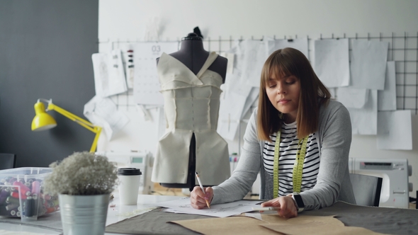 Professional Clothing Designer Is Sketching Then Receiving Message on Smartphone alt