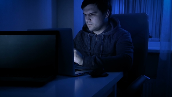 Footage of Young Man Wearing Hoodie and Eyeglasses Working at Computer alt