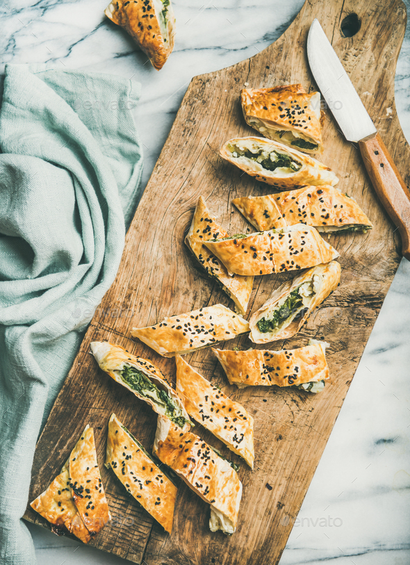 Freshly baked Turkish borek roll cut in slices on board - Stock Photo - Images