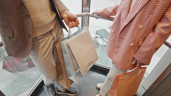 Stylish Couple In Glass Elevator In Shopping Centre alt