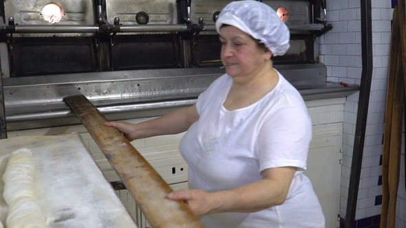 Traditional Italian Bakery. The Woman Baker Puts the Bread in the Oven for Baking