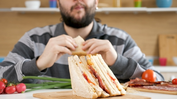 Man Entering the Kitchen, Taking a Seat and Starts Eating a Sandwich ...