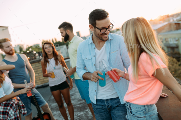 Group of happy friends having party on rooftop Stock Photo by nd3000