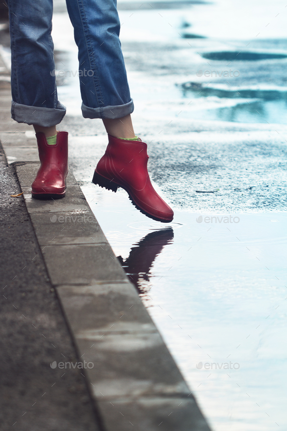 woman with red short boots standing on sidewalk next to a puddle - Stock Photo - Images