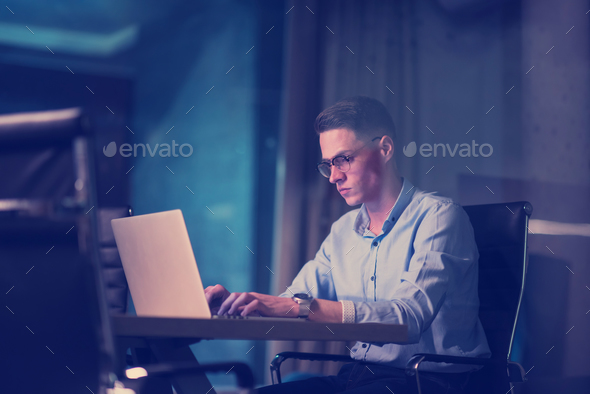 man working on laptop in dark office - Stock Photo - Images