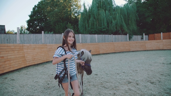 Pretty Girl Walks with a Beautiful Pony on the Arena. alt