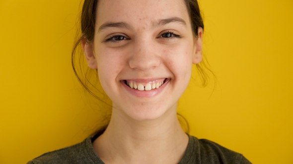 Smiling Teenage Girl on Yellow Background alt