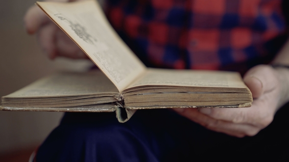 View of Wrinkled Male Hands Flipping Pages of an Old Book. alt
