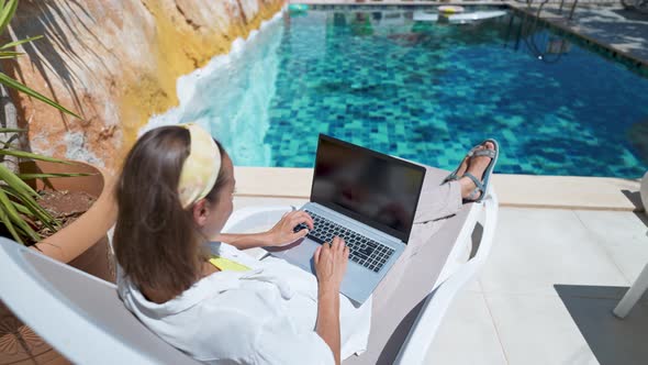 Camera Moving to Awoman Enjoying Relaxing By the Pool with Laptop Computer with White Empty Screen alt