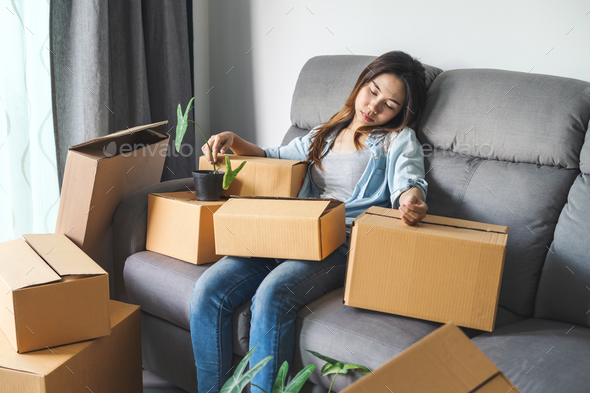 Young tried woman moving in new home, sitting and relaxing on sofa Stock Photo by kitzstocker