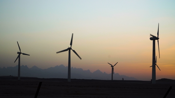 Beautiful Windmill Turbines Harnessing Clean, Green, Wind Energy Silhouetted in the Sunset Sky with alt