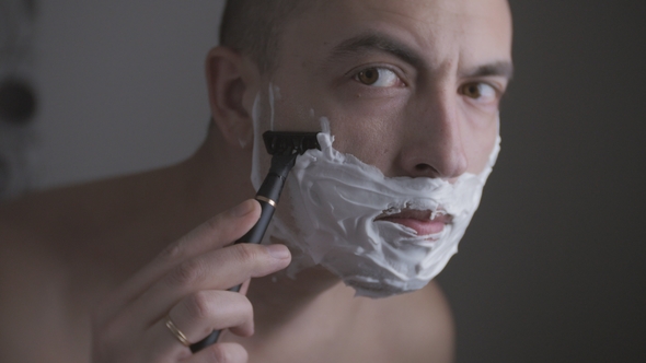 Man Shaving His Face with a Razor with the Help of a Special Foam alt