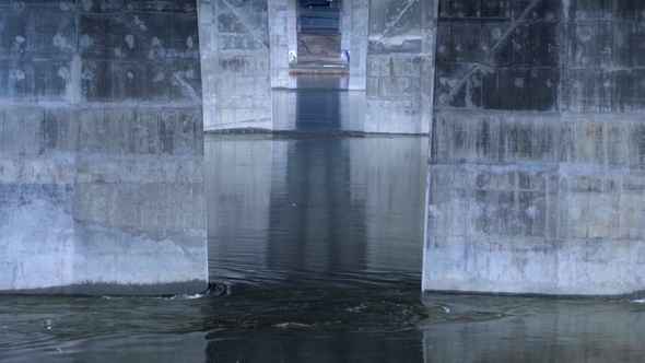 The Flow of the River Under the Bridge, the Industrial Bridge of Concrete Supports. alt