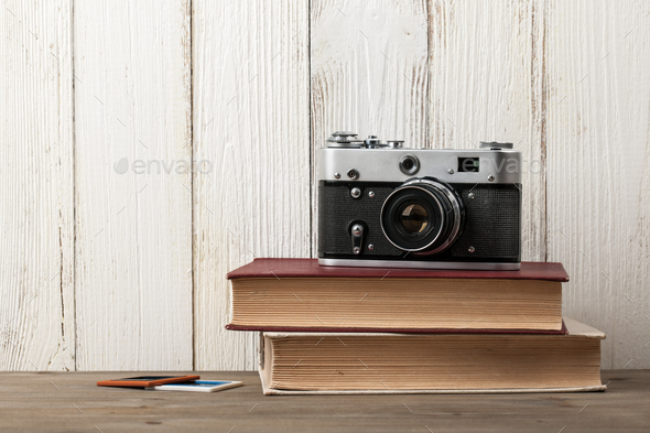 Retro film camera and books on wooden table