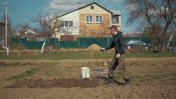 A Man Digs the Ground with a Shovel