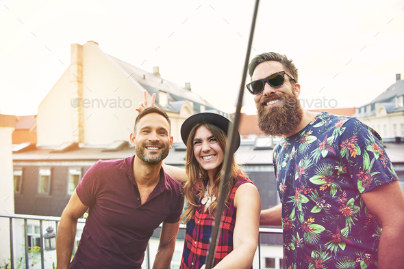Woman and two male friends stand on patio Stock Photo by UberImages