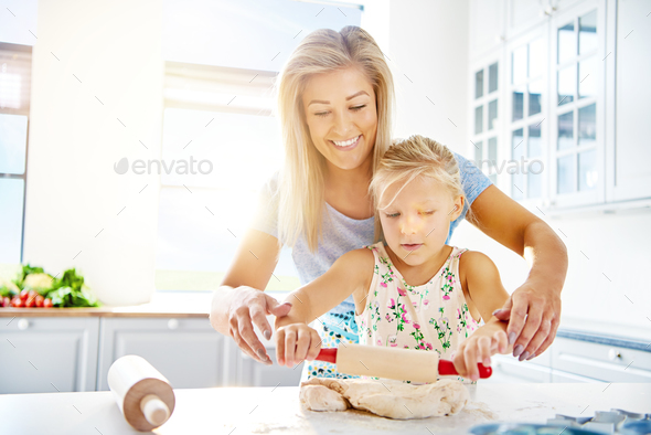 Cute little girl learning to roll out dough - Stock Photo - Images