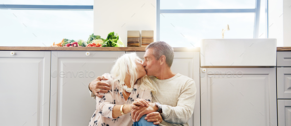 Elderly couple kissing on a kitchen floor - Stock Photo - Images