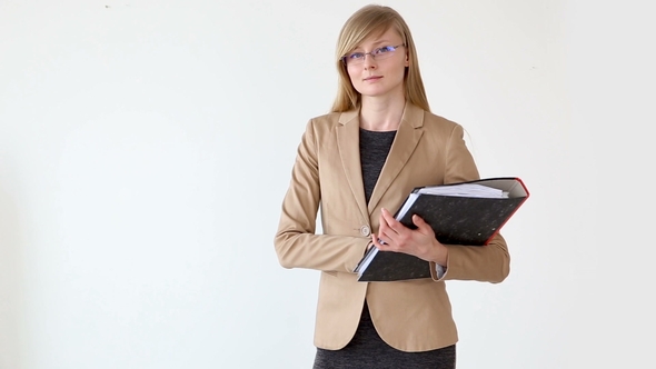 Young Beautiful Woman in Business Style with Glasses and Documents in Hands Posing Near White