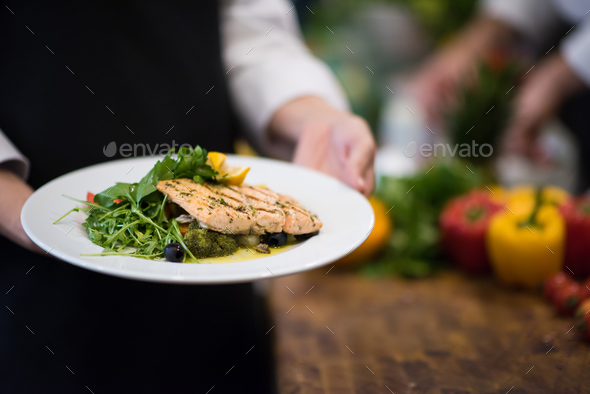 Chef hands holding dish of fried Salmon fish fillet - Stock Photo - Images