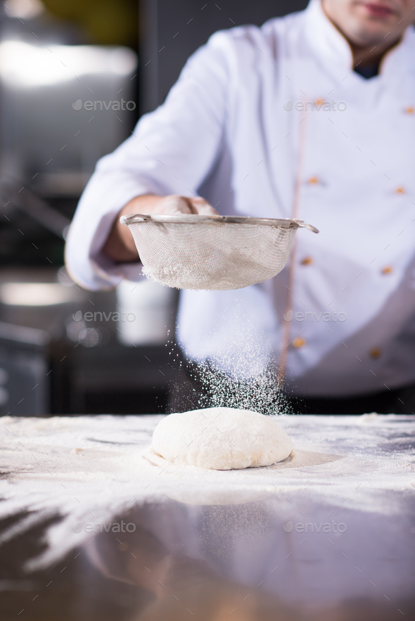 chef sprinkling flour over fresh pizza dough - Stock Photo - Images