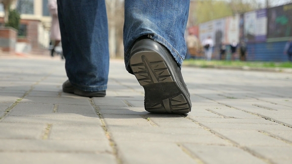 Male Feet in Black Shoes Walk along a City Sidewalk in Spring