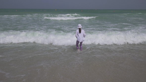 Teenage Girl in Clothes Joyfully Jumping in the Waves of Persian Gulf on the Beach of Dubai Stock alt