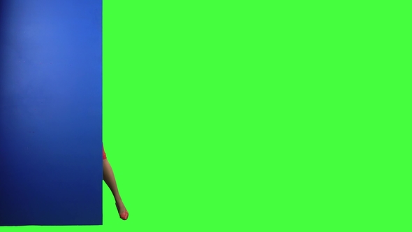 Girl Looks Out From Behind the Blue Board and Points at Her Hand . Green Screen alt