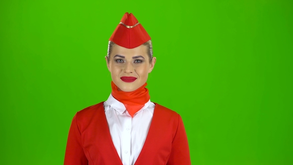 Stewardess in a Red Suit Winks a Slight Flirt. Green Screen alt