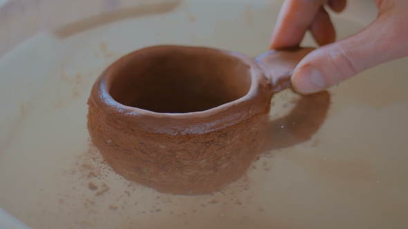 Potter Dipping Clay Cup in Water