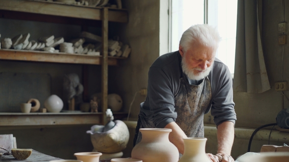 Experienced Potter Is Kneading Clay with His Hands on Working Table in Workshop. Creating Eathenware alt