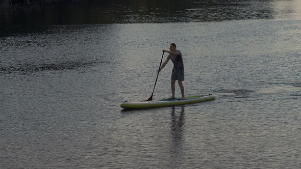 Long Shot, Sports Guy Rapidly Sails on the River Standing on the Sup