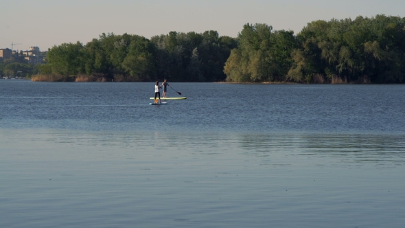 Very Long Shot, A Family Couple Performing A Walk on the River Standing on the Sups alt