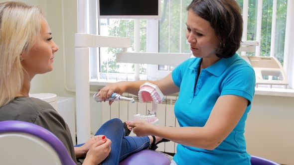 Footage of Female Dentist Teaching Patient How To Clean Teeth with Electric Brush alt