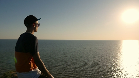 Smart Young Man Sits on the Black Sea Shore at Splendid Sunset in Slo-mo