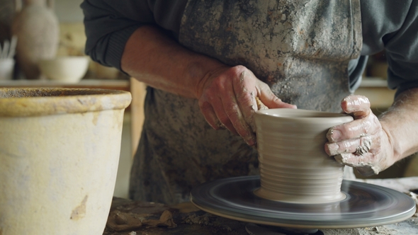 Shot of Half-finished Ceramic Vase Spinning on Potters's Wheel and Hands Molding Clay  alt