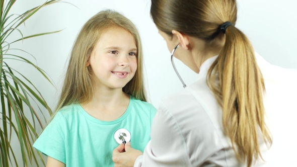 Pediatrician Talks To Smiling Girl and Listenes Heart Beat Using a Stethoscope