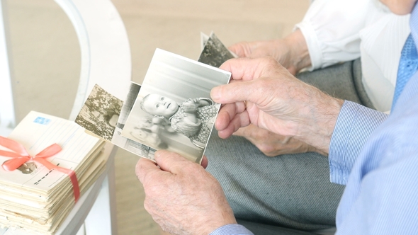 Hands of Happy Caucasian Elderly Couple Spending Time Together And Watching Old Photos