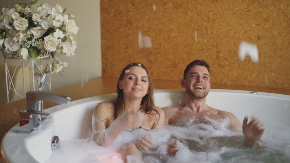 Cheerful Pretty Girl in Bathing Suit and Her Handsome Boyfriend Playing with Soap Foam alt
