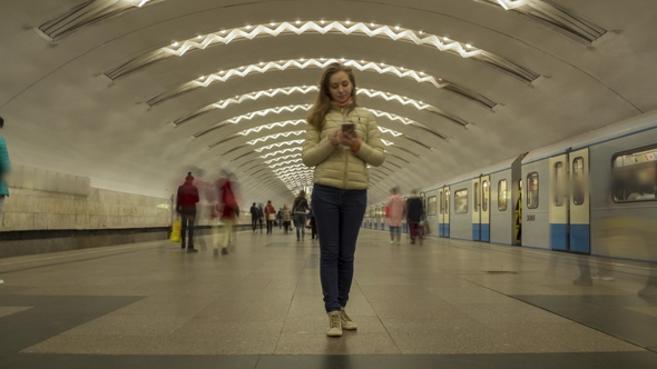 Woman Standing Still in Metro Station and Using Mobile Phone alt