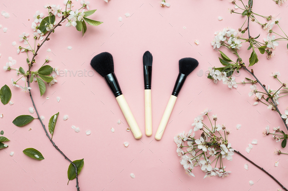 Decorative flat lay composition with cosmetics brushes and flowers Stock Photo by Vladdeep