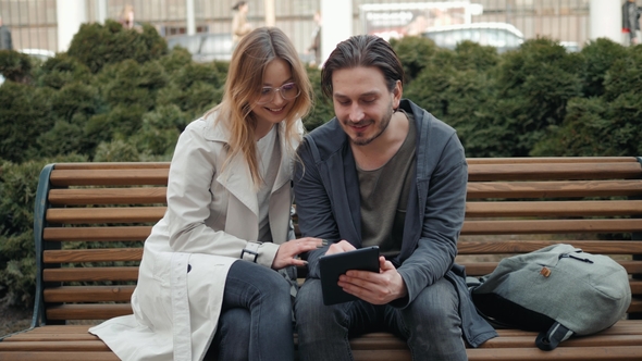 Couple Sitting on Public Bench and Using Tablet, Man and Woman Students Near University Campus alt